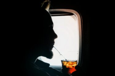 man sipping drink beside window