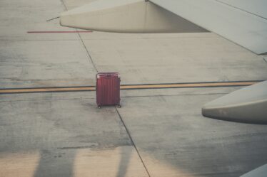 red hard shell luggage by an airplane wing