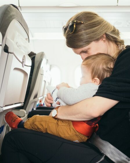woman carrying baby while sitting on gray seat