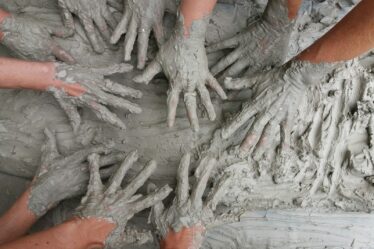 people's hand on gray mud