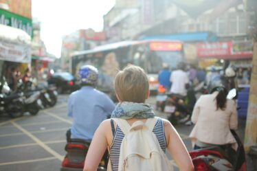 woman wearing backpack walking on road